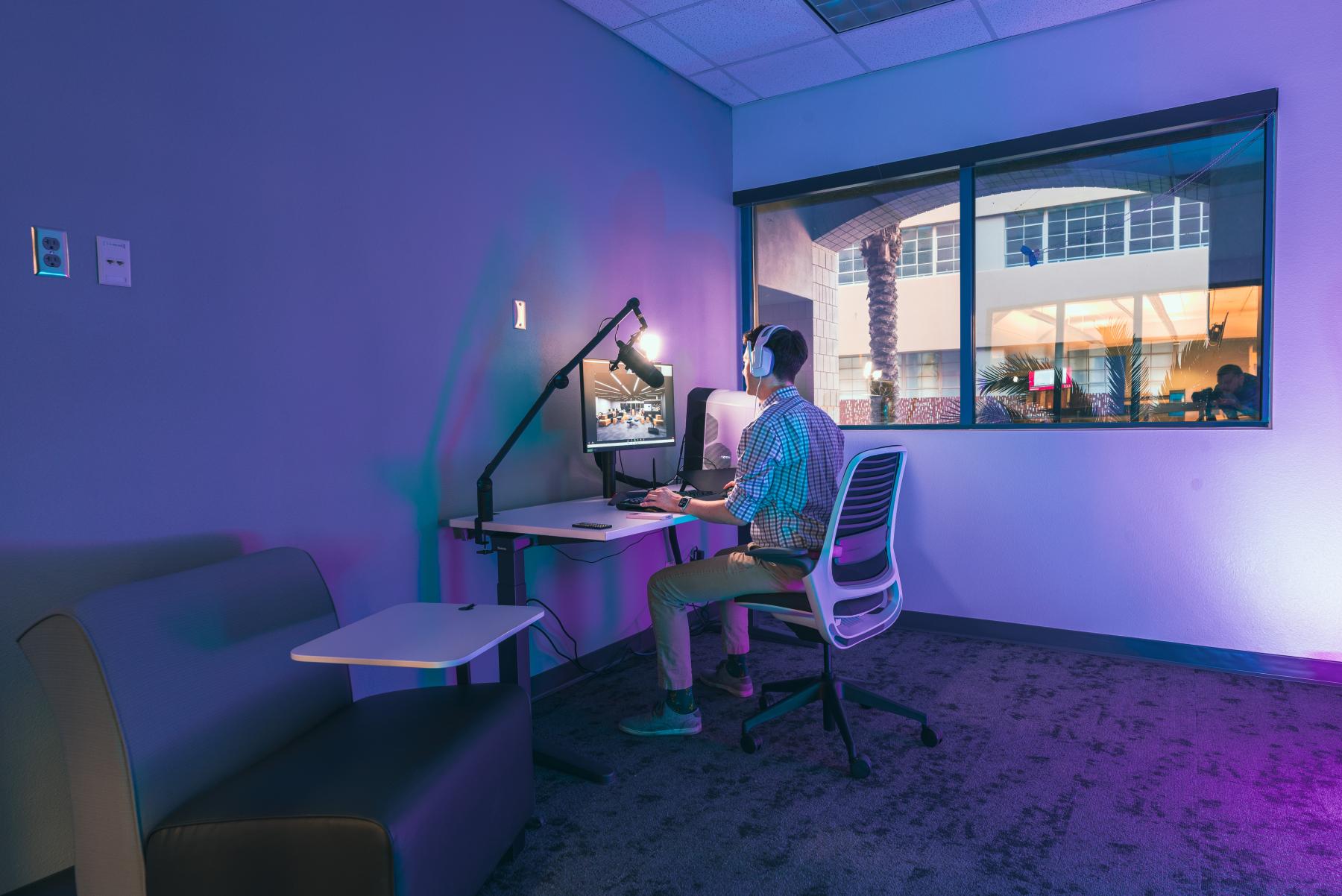 Man sitting in Zoom Innovation Studio with headphones on working on the computer