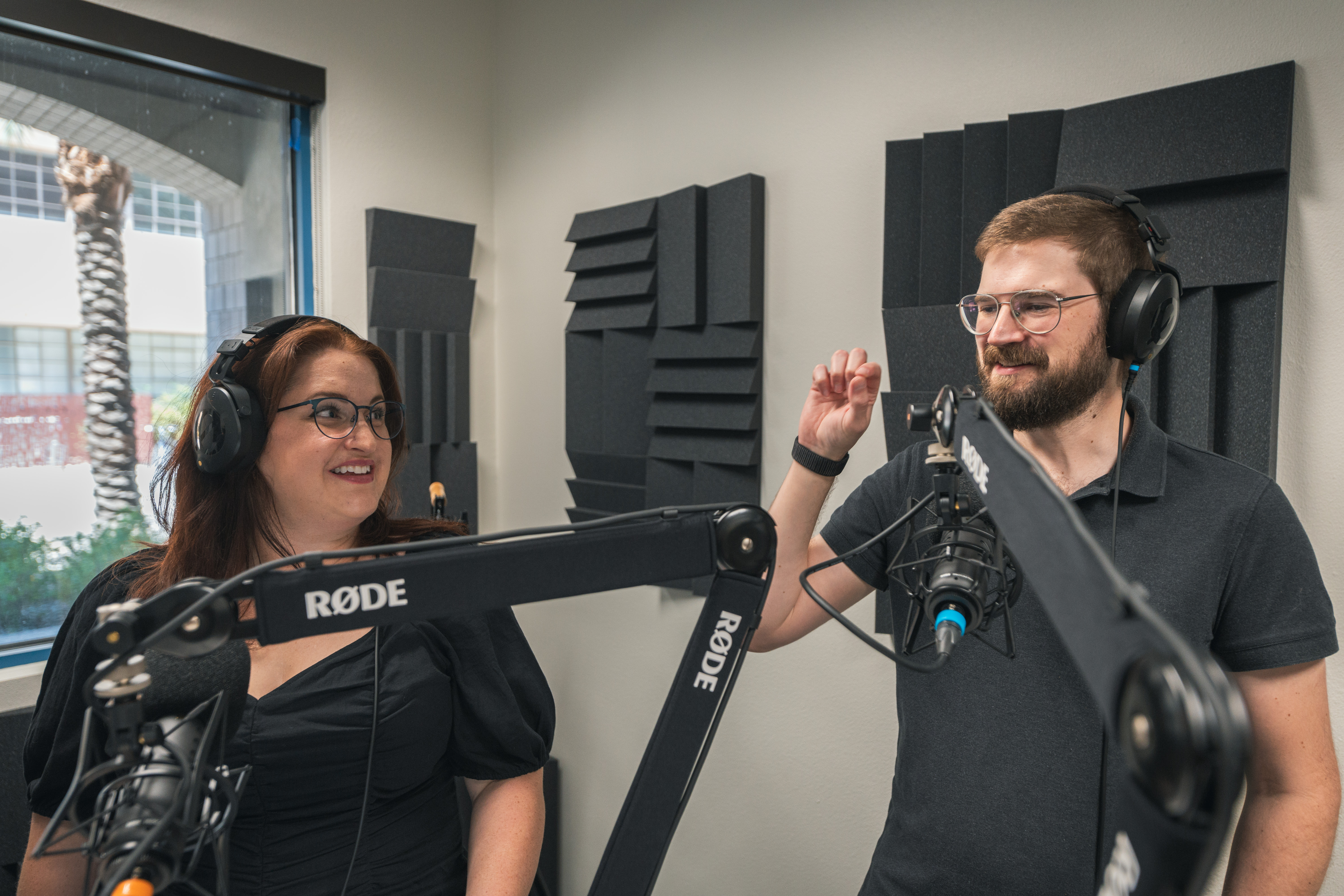 A man and a woman happily talking while recording a podcast