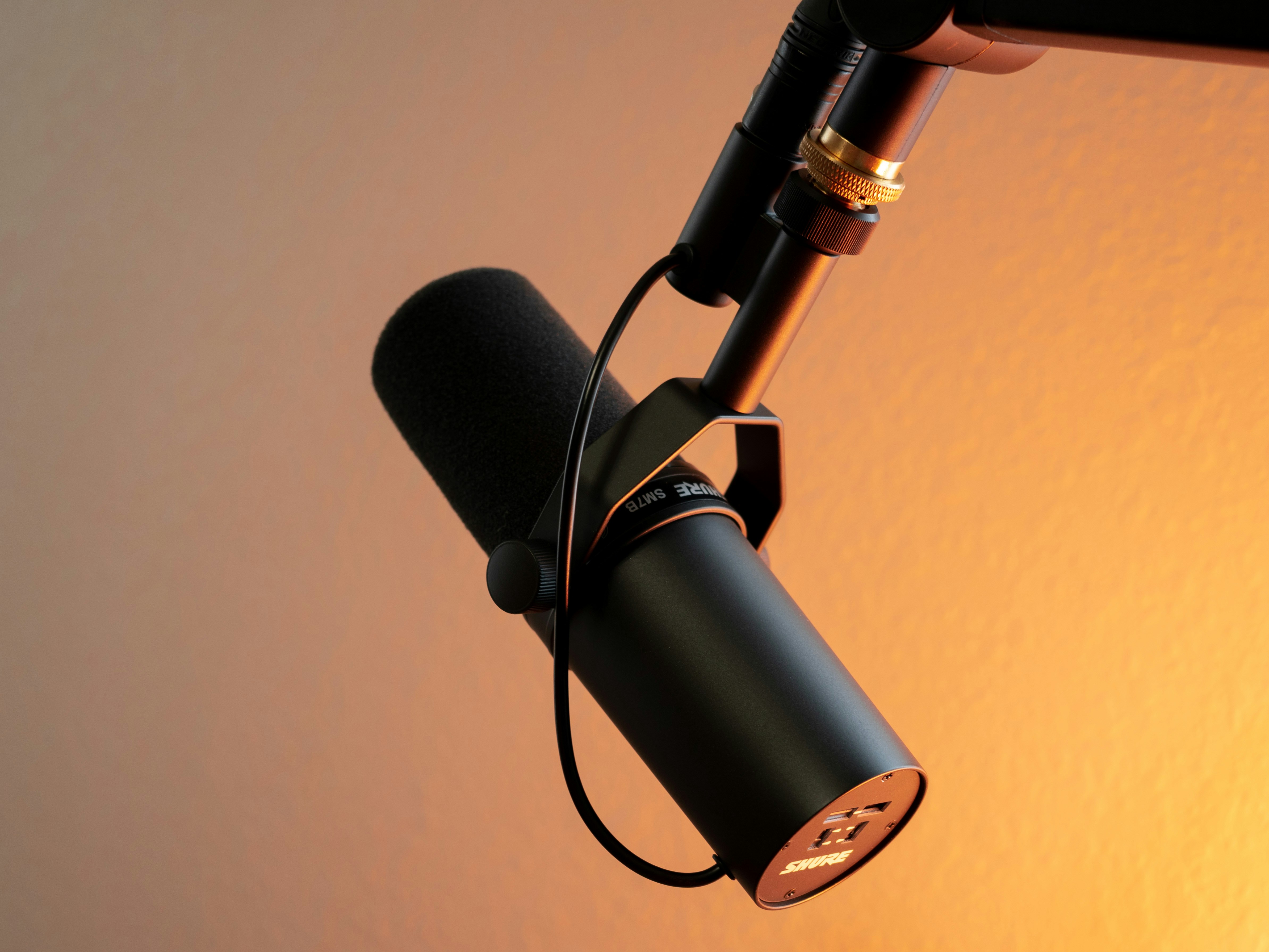 black podcasting microphone with a yellow lit background