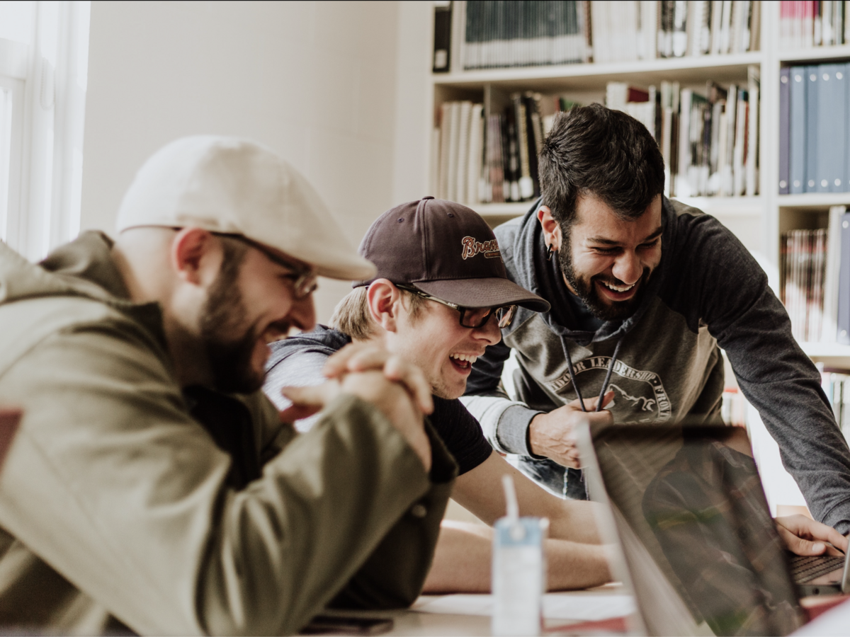 young men laughing and collaborating over group work